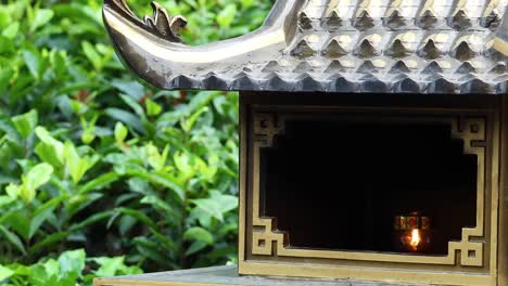 a lantern burns inside a traditional shrine