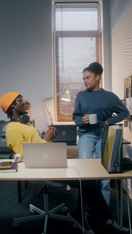 two young adults having a conversation in a modern office