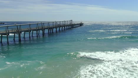 flying out slowly towards the end of gold coasts sand pumping jetty on a clear morning with a peaceful swell rolling in