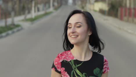 joven atractiva en un vestido con flores moviéndose hacia la cámara y sonriendo