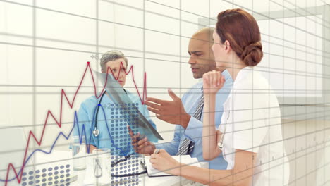medical team reviewing clipboard data while displaying red blue line graphs in medical office