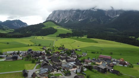 Alpine-Serenity:-4K-Aerial-Drone-Shot-of-Foggy-Drive-from-Graz-to-Hallstatt,-Cars-Wind-Through-Austrian-Countryside-with-perfectly-mowed-green-fields-and-Breathtaking-Alps-Panorama