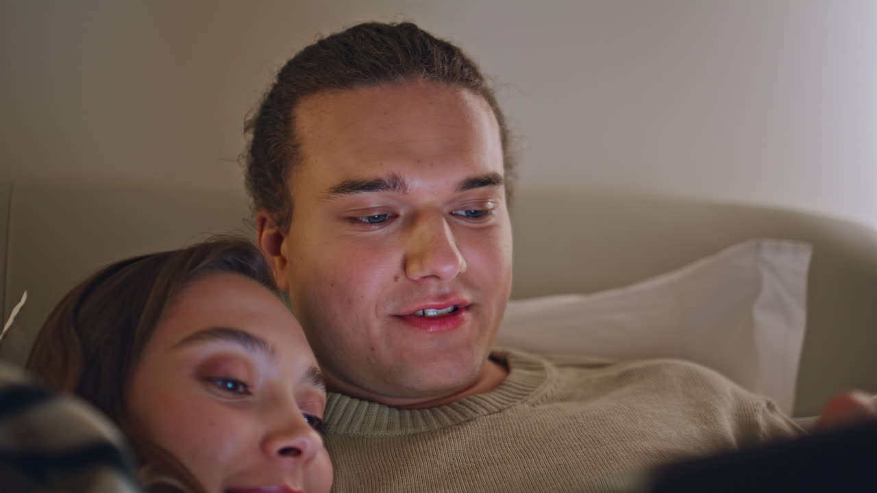 Home couple browsing website on tablet lying bed closeup. Affectionate partners