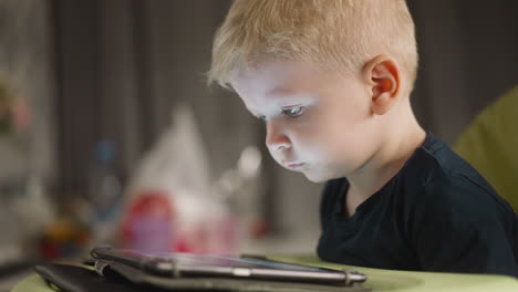 Toddler-boy-smiles-while-watches-funny-videos-via-tablet