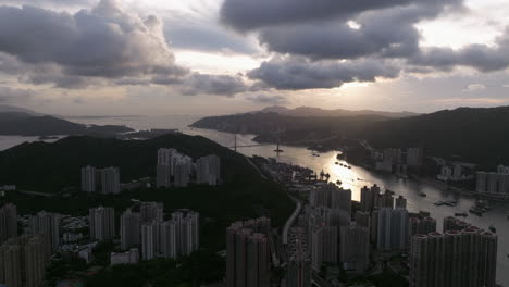 urban coastal scenery with suspension bridge and high-rise buildings during golden hour, facing the sun