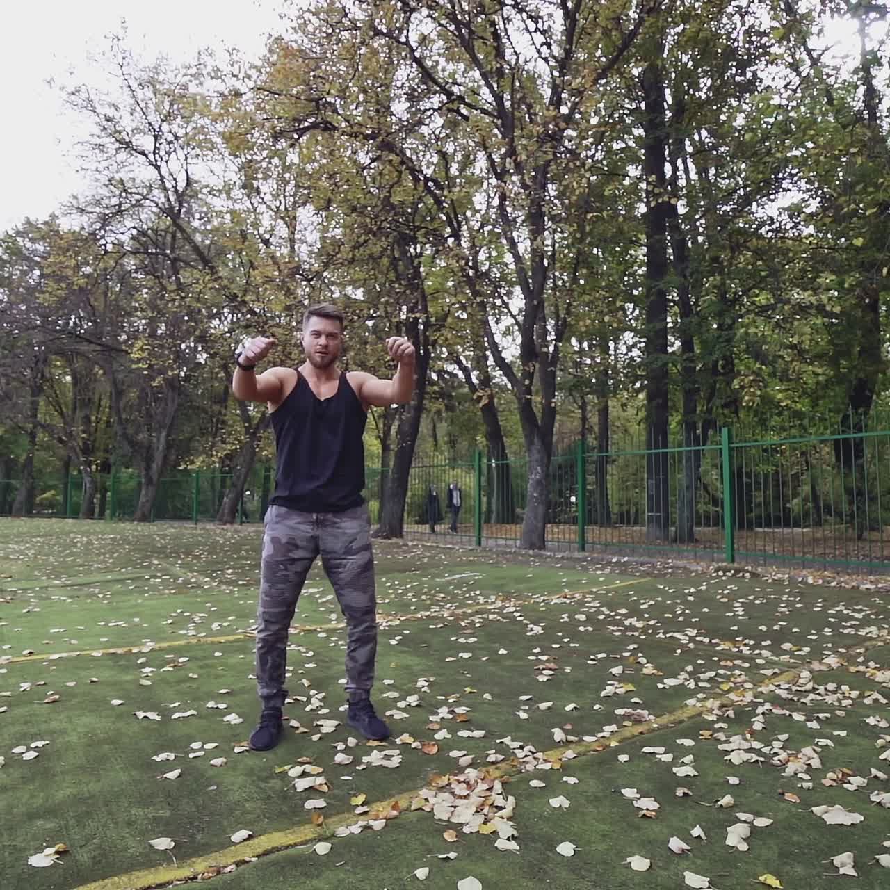 Handsome bearded sportsman outdoors. Muscular athlete doing exercises in the open air in autumn. Slow motion.