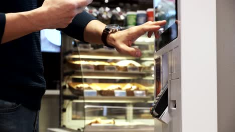 a young man buys a telephone in a contactless way in a self-service machine. men pay by phone. close up. 4k video