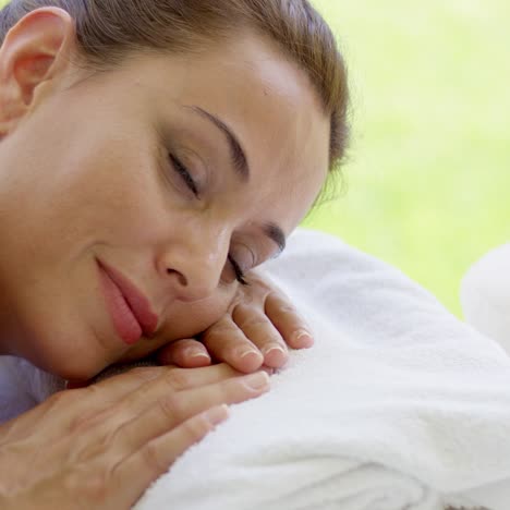 Woman-with-hair-up-in-a-bun-rests-on-folded-towel