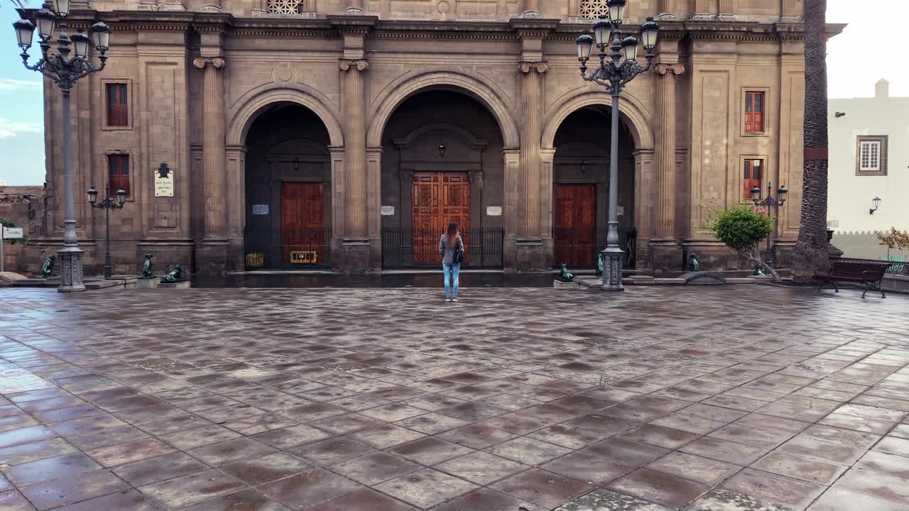 Donna che cammina verso la storica Cattedrale di Las Palmas in una giornata nuvolosa a Gran Canaria, Spagna, visitando un luogo simbolo