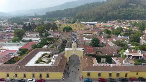 Vista-Aérea-Del-Arco-De-Santa-Catalina-Frente-A-La-Iglesia-De-La-Merced,-En-Antigua,-Guatemala---Ascendente,-Inclinación,-Disparo-De-Drones