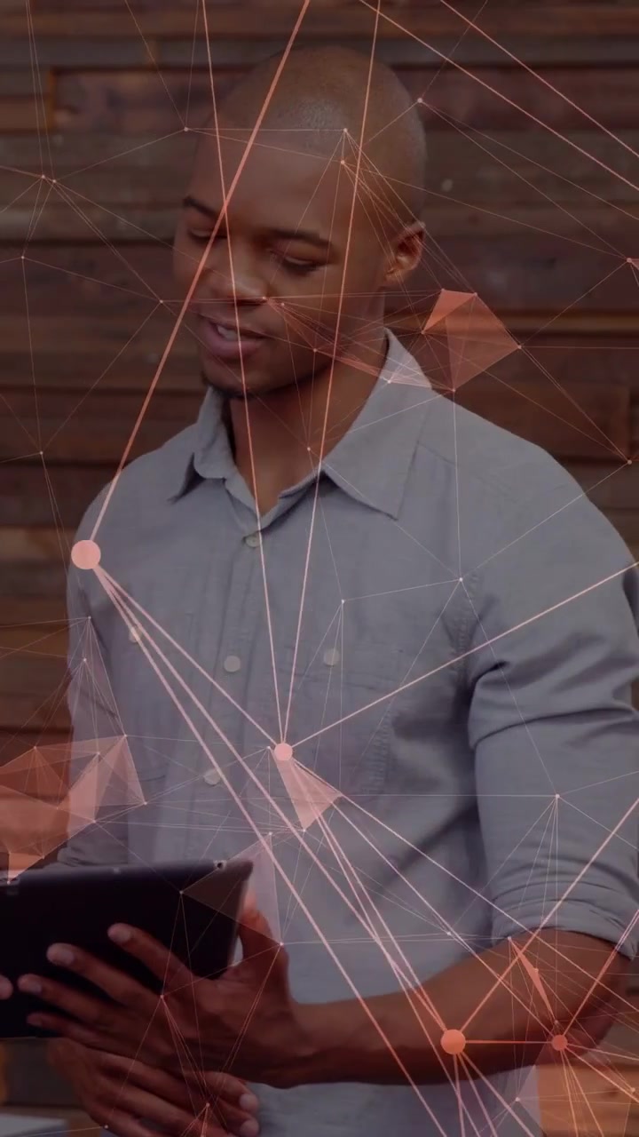 Vertical video: Exec tapping tablet, peer taking over showing tech data over slat wall net overlay
