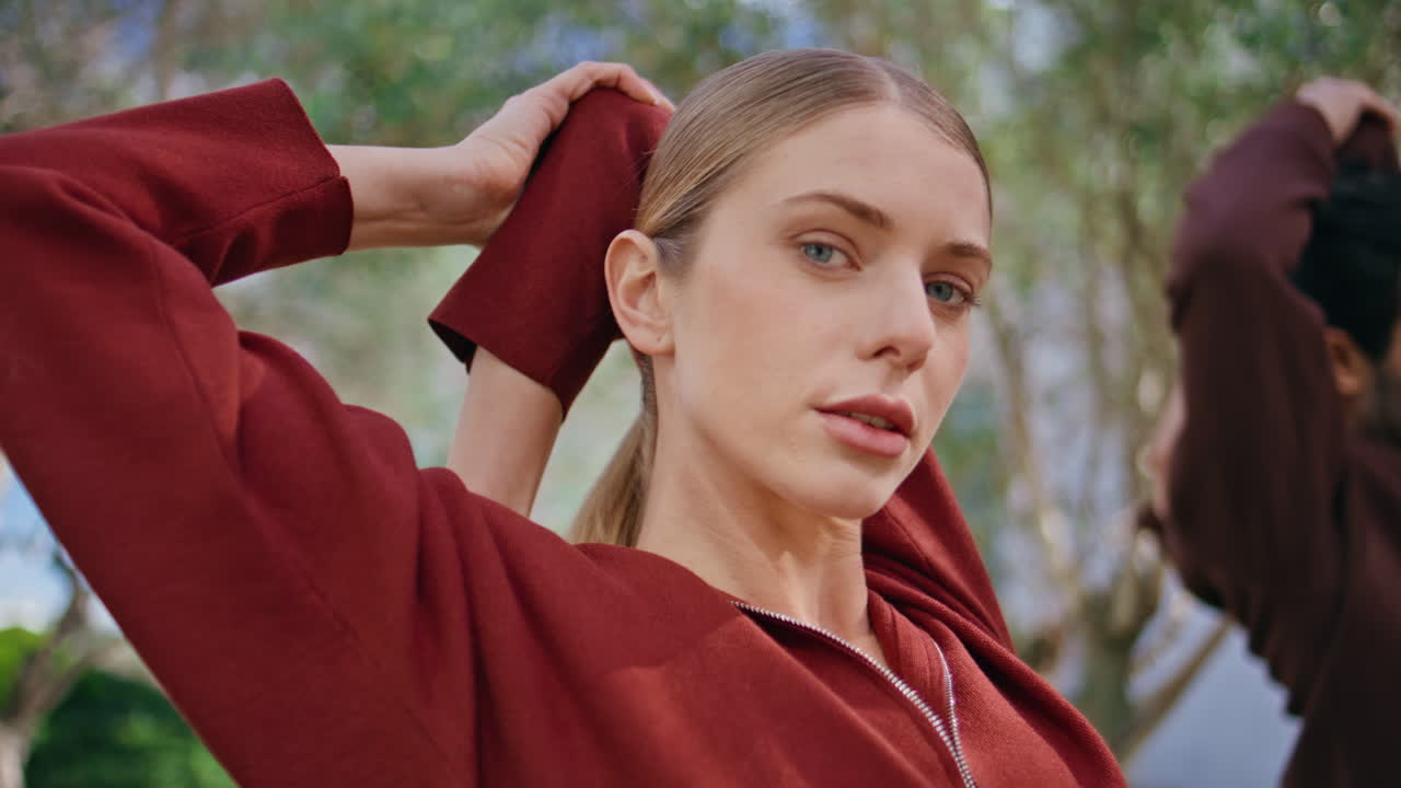 Athletic girl warming body in green park. Closeup sportswoman looking
