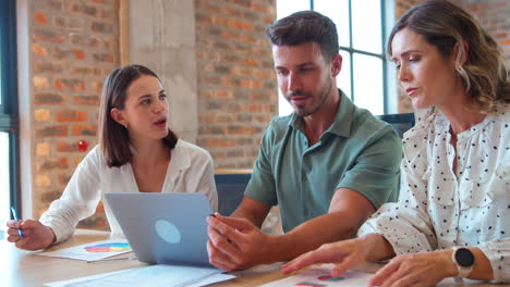 Male-And-Female-Business-Colleagues-With-Laptop-And-Documents-Meeting-In-Modern-Office