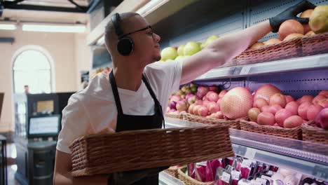 man worker stocking the fruits in supermarket while listen to the music, side view