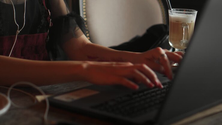 Young pretty woman in eyeglasses is working in cafe, listening to music and smiling.