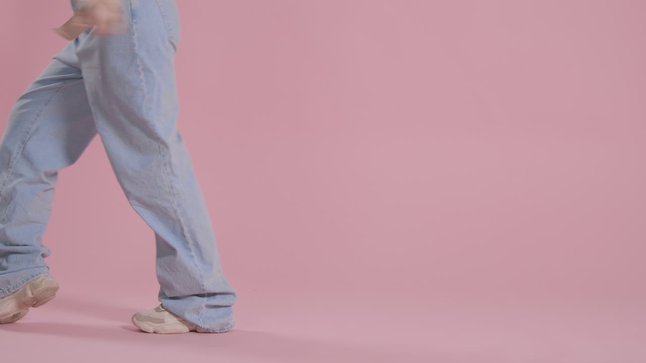 분홍색 스튜디오 배경 2에서 즐겁게 춤추는 여성의 다리와 발에 가까이