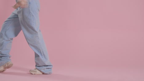 close up on legs and feet of woman having fun dancing against pink studio background 2