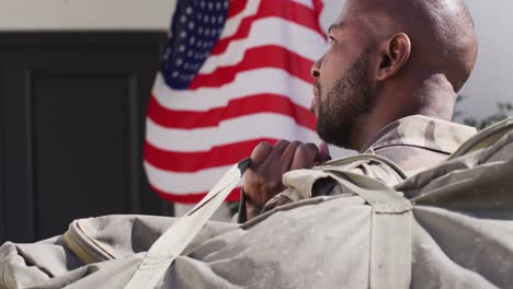 un soldado afroamericano regresando a casa con la bandera de los estados unidos en la puerta.