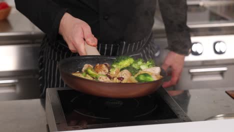 chef cooking pasta with chicken and vegetables