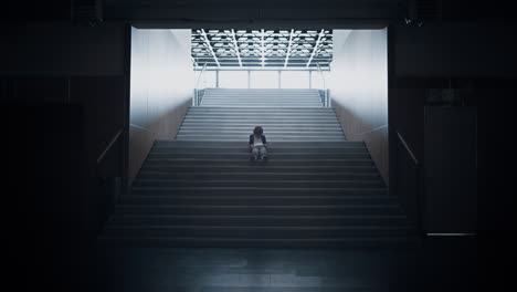 Lonely-teen-guy-sitting-on-dark-staircase-alone.-Schoolboy-hiding-in-empty-hall.