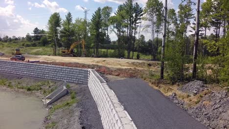 retaining wall being constructed beside a pond and new road drone follows the wall