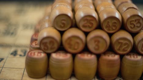fantasía cinematográfica suave soñadora girando hacia adelante macro tiro de bingo barriles de madera en una fila, figuras de madera, viejos números de fondo, juego de mesa vintage, cámara lenta 120 fps video gimbal comercial