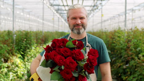 cheerful middle age man with roses in flower greenhouse