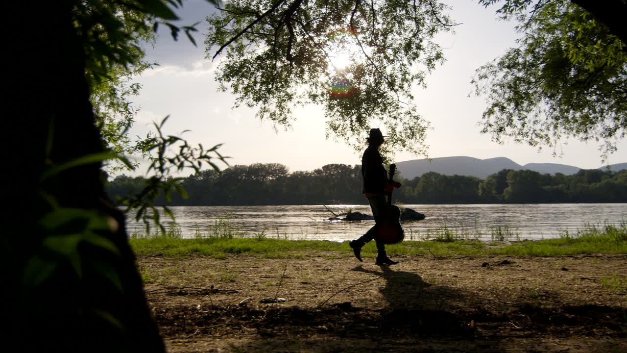 Man Walking Along a Riverbank in a Forest