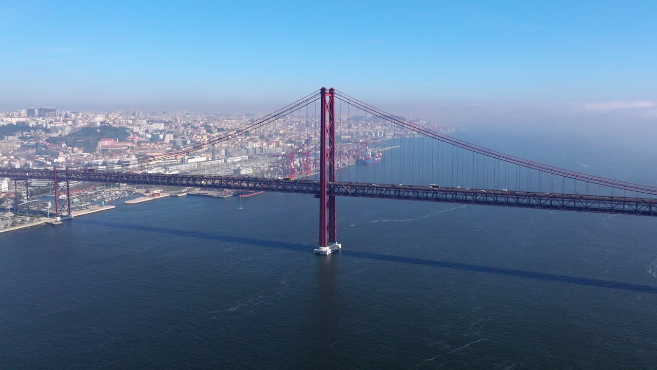 Aerial drone wide establishing shot of iconic and famous Lisbon red bridge by Christ statue in Lisbon, Lisboa, Portugal. Sunny, bright, blue sky with clouds