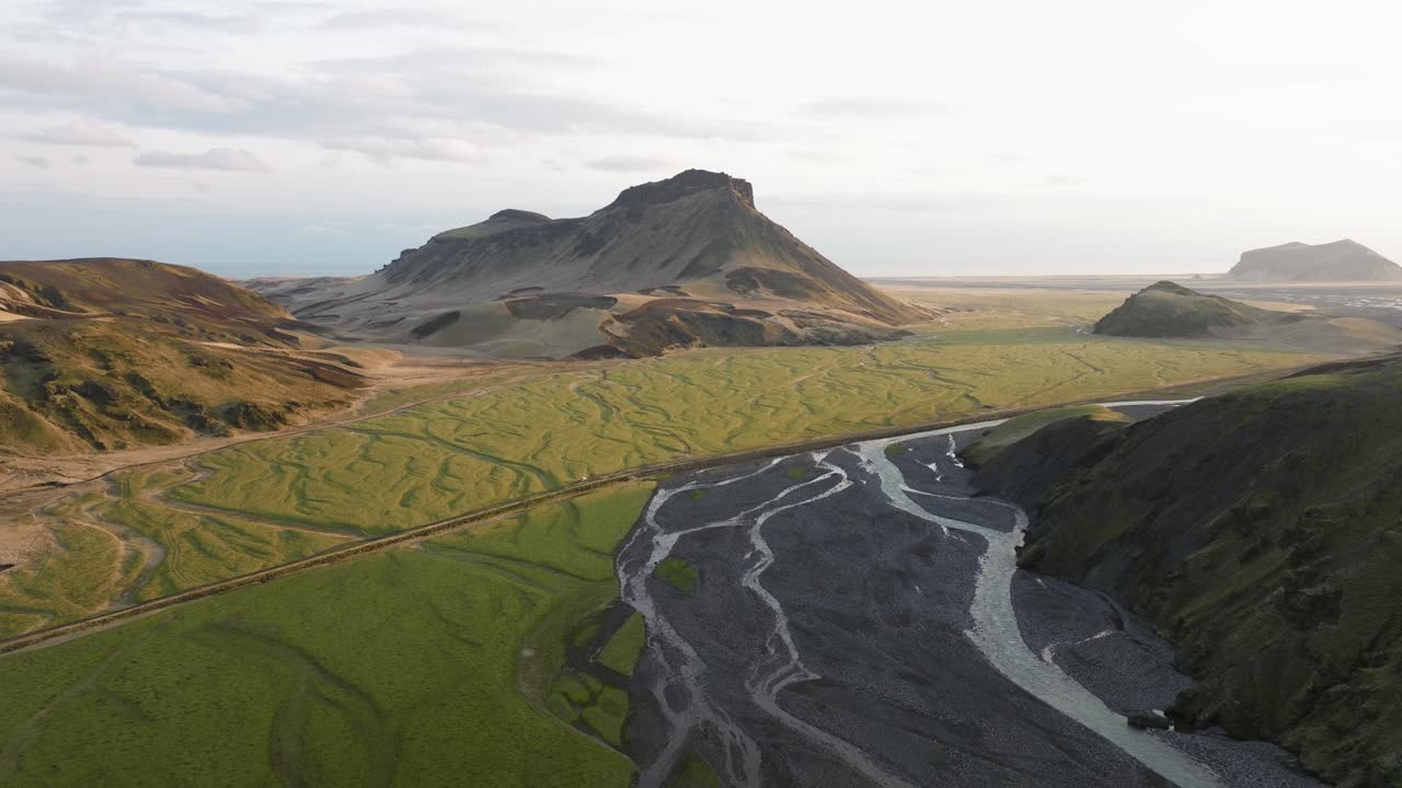 아이슬란드 부르펠의 다양한 지형을 가로질러 흐르는 푸른 평야와 인 강의 드론, 은 빛 아래 배경에 보이는 산