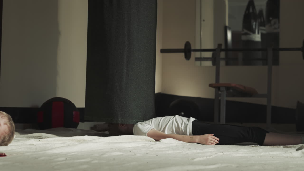 아이는 스포츠 센터에서 놀라운 부이 에 누워있다. 작은 소녀는 체육관에서 무술 연습에 지쳤습니다. 아이는 바닥에 휴식을 취합니다.