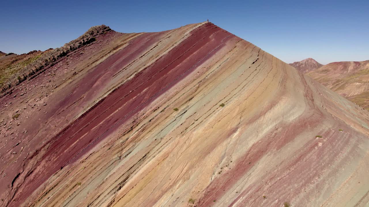 Gli strati vibranti di roccia in questo paesaggio montano mostrano una gamma di colori, inclusi rosso, arancione e giallo.