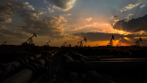 pipeline and working oil pump jacks in a against sunset extracting crude oil. pumping fossil oil is one of the methods of energy generation from renewable energy sources