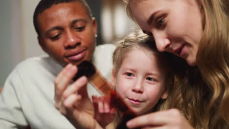 pretty lady with daughter and black husband looks at film