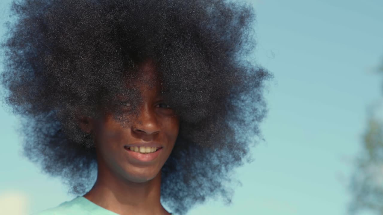 adolescente afroamericano con un enorme afro mirando a la cámara