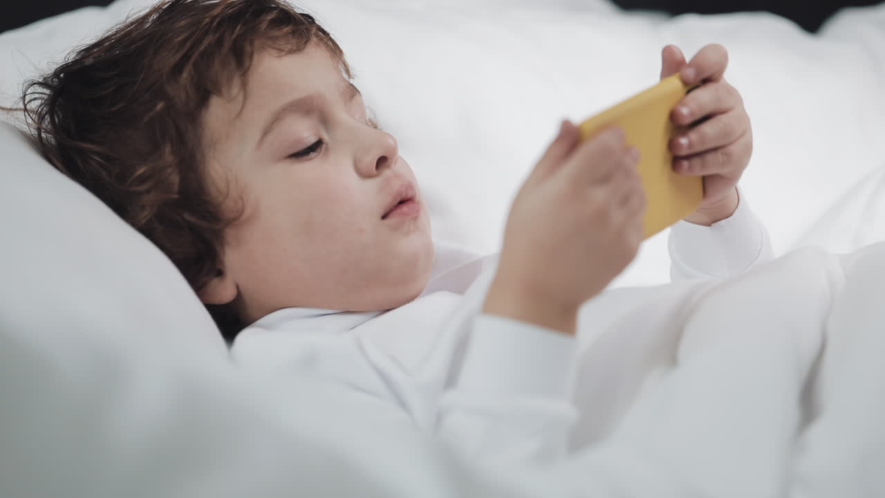 Child using mobile phone in bed