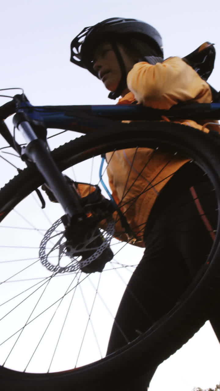 Ciclista di mountain bike donna che porta la bicicletta nel bosco