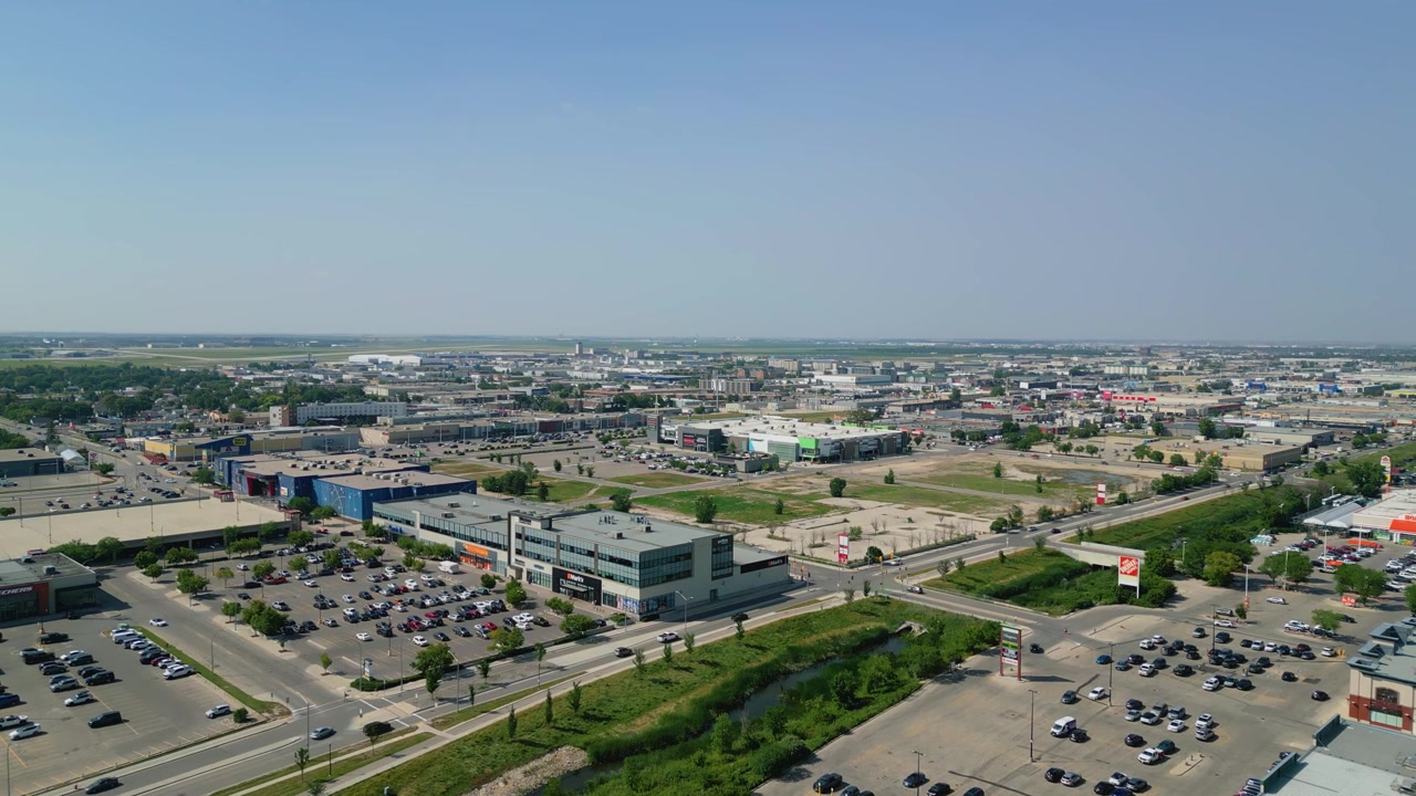 Slow forward aerial drone shot establishing Winnipeg’s west side, featuring Richardson International Airport, Polo Park, industrial districts, and surrounding neighbourhoods