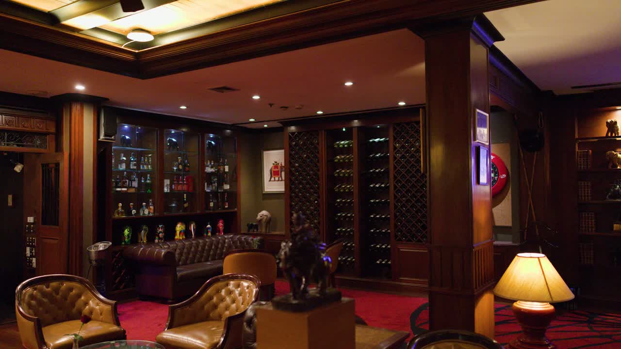 Luxurious lounge bar with leather seating, wood paneling, ambient lighting, and stationary camera movement