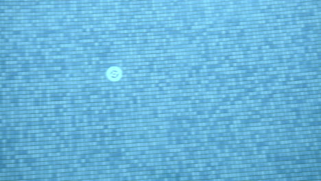 view to mosaic tiled bottom of swimming pool through clear water