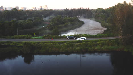 a white car drives past a broken down vehicle on a bridge near homebush, sydney