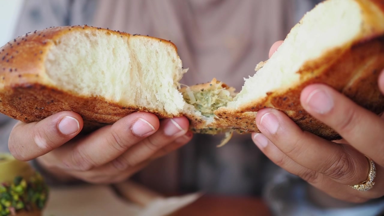 Person Tearing Open a Fresh Poppy Seed Bread Roll