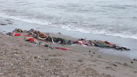 discarded clothes and fabric rubbish, resulting from fast fashion, polluting the beach in tropical island destination in southeast asia