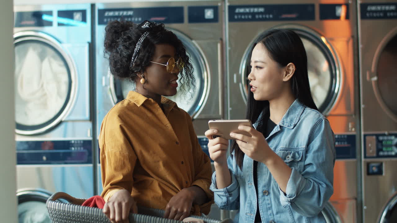 스마트폰으로 사진이나 비디오를 보고 이야기하는 다민족의 세련된 어린 소녀들