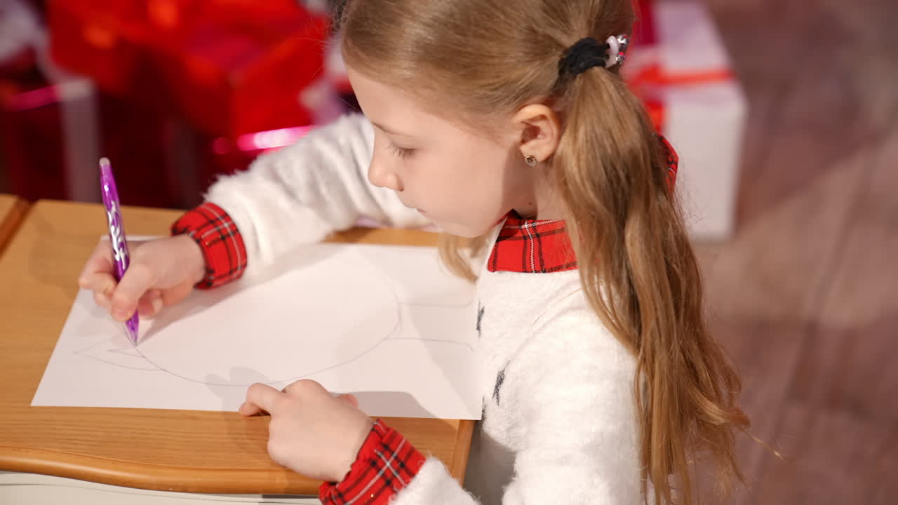 Cute child paints a picture with a pen at home. Little girl draw a picture for santa in New Year in the room. Profile view.