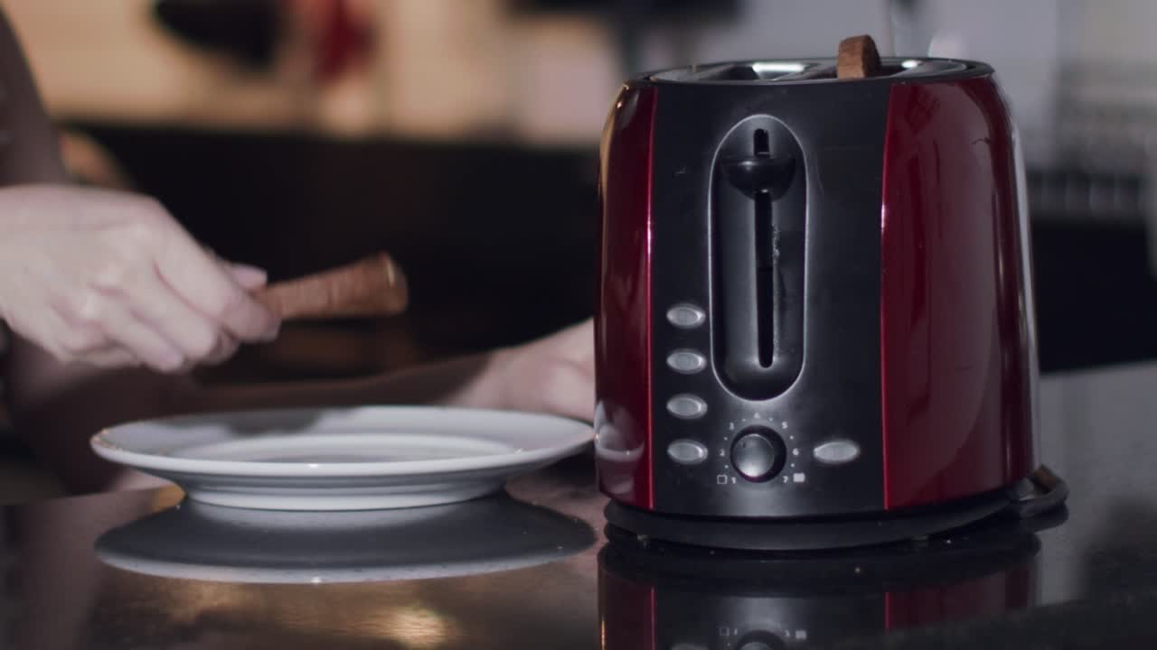hands of a caucasian model taking slices of bread from a toaster and placing them on her plate, close up