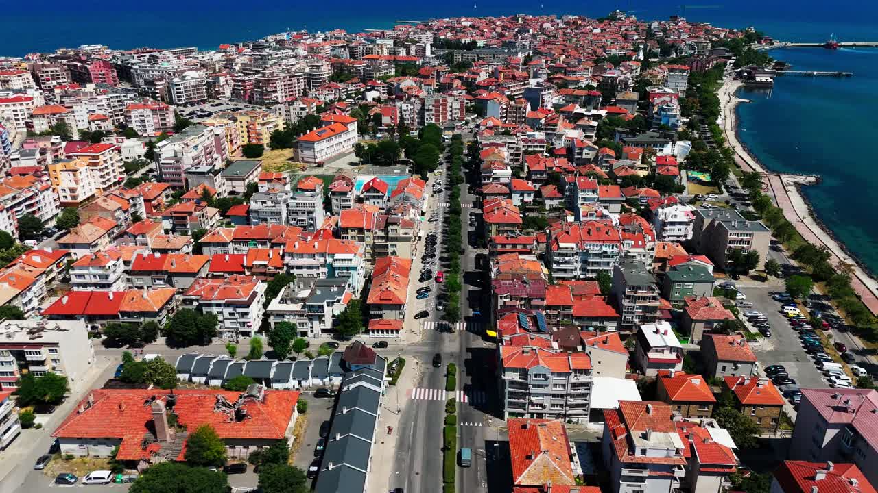 Un drone segue una strada principale di Pomorie verso il mare, evidenziando la disposizione costiera della città e le acque circostanti.