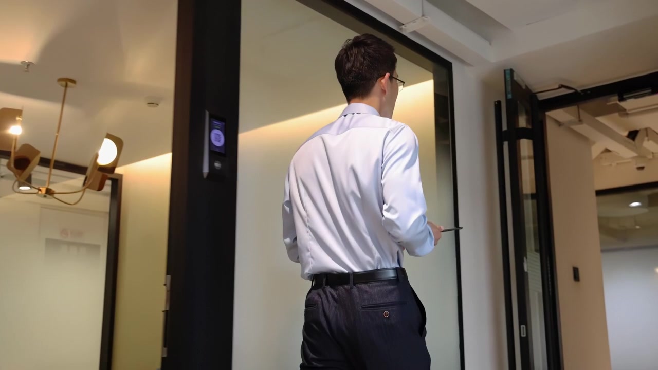 Confident businessman in a formal suit holding a tablet computer walks through the corridor in front of conference room symbolizing a journey towards success and opportunities in corporate environment