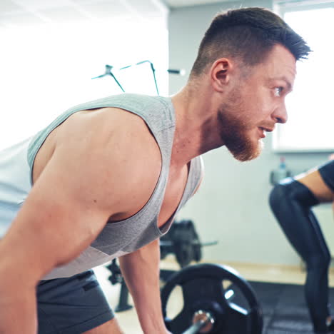 muscular man and a young woman lifting heavy weights at gym. fitness couple doing workout in the sport club. athletic couple finishes the exercise together and puts barbells on floor.