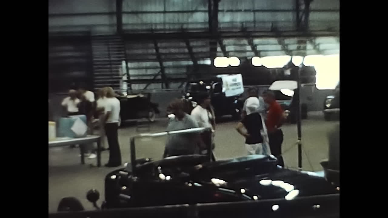 Person Standing Next to Car in 1970s USA Parking Lot. CIRCA USA - 1970s: A photo capturing a person standing alongside a car in a parking lot during an old car show in 1970s USA.